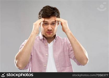mind, health problem and stress concept - unhappy indian man suffering from headache over grey background. unhappy young man suffering from headache