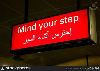 Mind your step sign in an international airport in Middle East with Arabic information