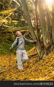 Mindful forest hike. Sporty middle-aged woman, hiking the forest trails, enjoying her surroundings on a beautiful autumn day, feeling harmony with nature. Mindful forest hike