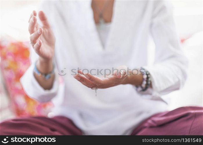 Mindful woman sitting in lotus position, meditating, performing respect gesture with her hands. Spiritual awakening.. Respect