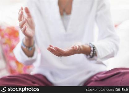 Mindful woman sitting in lotus position, meditating, performing respect gesture with her hands. Spiritual awakening.. Respect