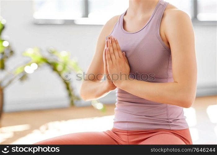 mindfulness, spirituality and healthy lifestyle concept - close up of woman meditating in lotus pose at yoga studio. woman meditating in lotus pose at yoga studio