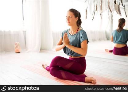 mindfulness, spirituality and healthy lifestyle concept - woman meditating at yoga studio. woman meditating at yoga studio