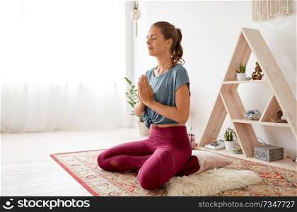 mindfulness, spirituality and healthy lifestyle concept - woman meditating in lotus pose at yoga studio. woman meditating in lotus pose at yoga studio