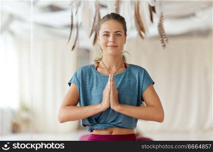 mindfulness, spirituality and healthy lifestyle concept - woman with namaste gesture meditating at yoga studio. woman with namaste gesture at yoga studio