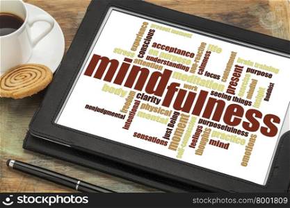 mindfulness word cloud on a digital tablet against a grunge wood table with a cup of coffee