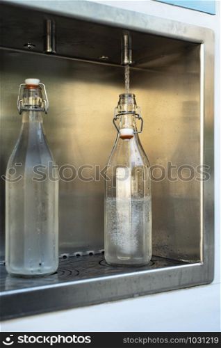 Mineral Water machine on the street. Filling mineral water bottles from a water dispenser. Pay and load drinking water.