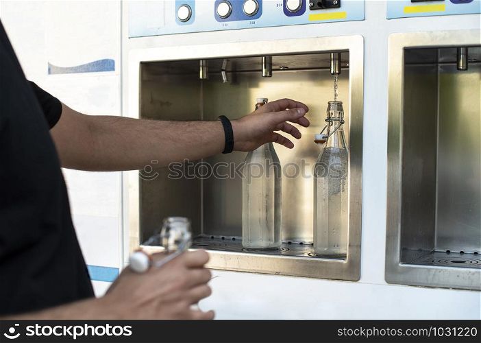 Mineral Water machine on the street. Filling mineral water bottles from a water dispenser. Pay and load drinking water.