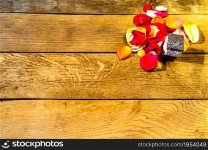 Mini cakes with flower petals on wooden table
