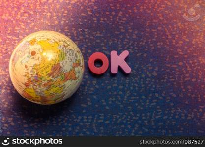 Mini globe model beside word OK with letter blocks