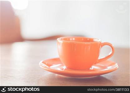 Mini orange coffee cup on wooden table, stock photo