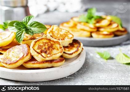 Mini pancakes on plate, top view table scene over a gray background.