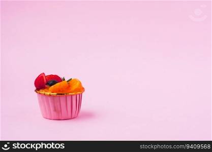 Mini paper cup of fruit or orange sponge cake on pink background for bakery, food and eating concept