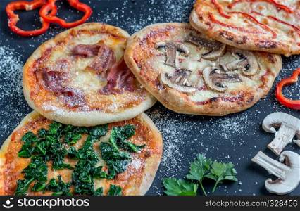 Mini pizzas with various toppings on the wooden board