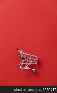 Mini shopping trolley for shopping on red background, consumer concept, minimalism, top view, copy space. Sale mock up