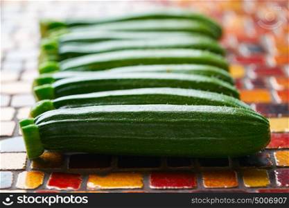 Mini zucchini vegetables in a row on red brown tiles table