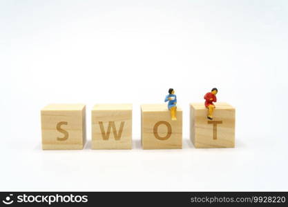 Miniature 2 people sitting on wood word SWOT using as background business concept and Strategy concept with copy space for your text or design.