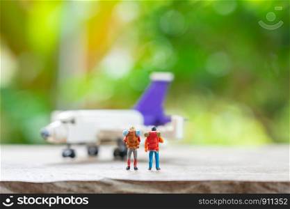 Miniature 2 people standing travel planner with Plane model as background travel concept with copy space.