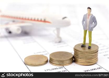 Miniature businessman and stack coins on statement and the airplane behind. saving and loan concept.