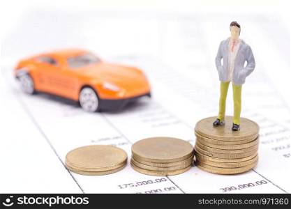 Miniature businessman and stack coins on statement and the car behind. saving and loan concept.
