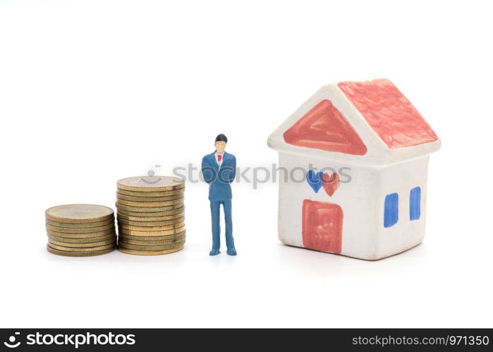 Miniature businessman standing on coins and the house behind. saving and loan concept.