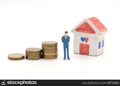 Miniature businessman standing on coins and the house behind. saving and loan concept.