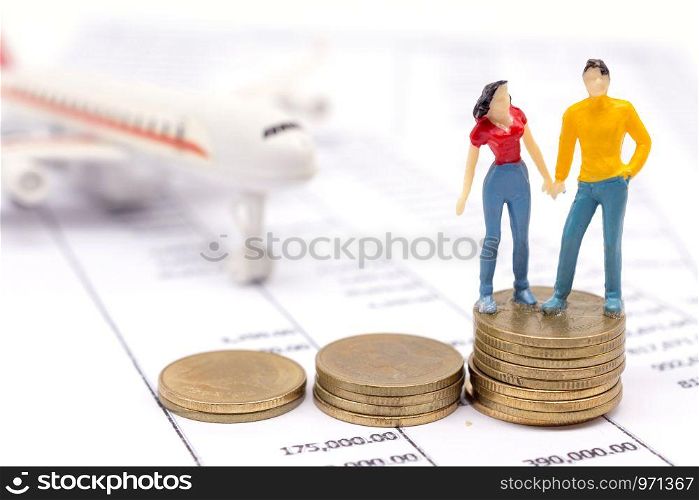 Miniature couple people and stack coins on statement and the airplane behind. saving and loan concept.