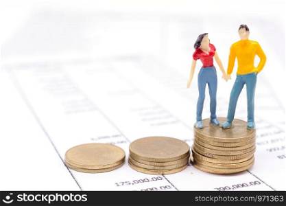 Miniature couple people and stack coins on statement. saving and loan concept.