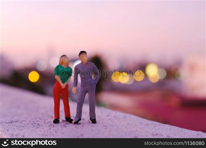 Miniature couple people figure standing at rooftop seeing sunset view of the city, valentines day concept
