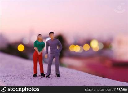 Miniature couple people figure standing at rooftop seeing sunset view of the city, valentines day concept