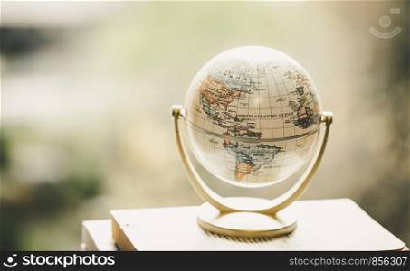 Miniature globe model standing on a stack of books. Symbol for travelling.