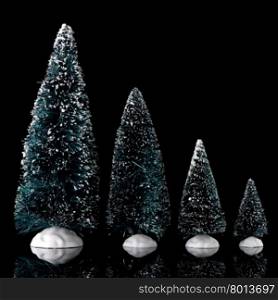 Miniature green pine trees with white snow on black background.