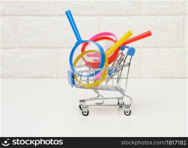 miniature metal trolley and plastic magnifier on a white background. The concept of search and selection of purchases, savings
