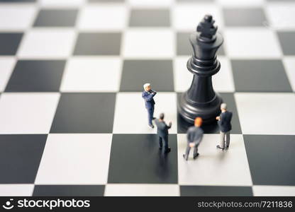 Miniature people businessmen standing on a chessboard with a chess piece on the back Negotiating in business. as background business concept and strategy concept with copy space.