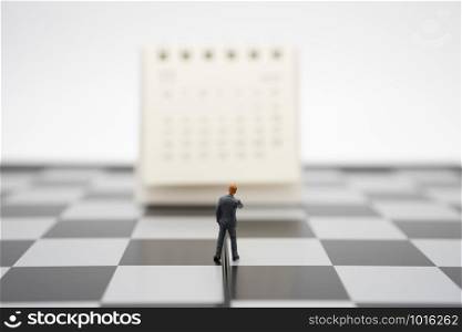 Miniature people businessmen standing on white calendar using as background business concept and finance concept with copy space for your text or design.