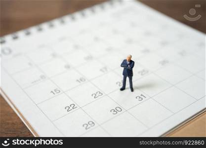 Miniature people businessmen standing on white calendar using as background business concept and finance concept with copy space for your text or design.