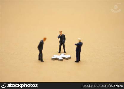 Miniature people businessmen standing on white Jigsaw. The concept used in selecting personnel to participate in the organization. with copy space.
