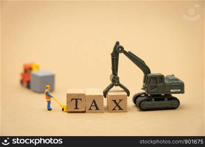 Miniature people Construction worker standing with wood word TAX using as background business concept and finance concept with copy space for your text or design.