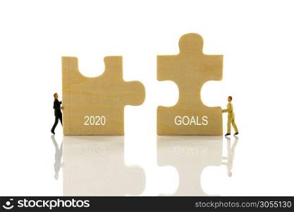 miniature people solving the puzzle problem how to set the goals for 2020. bringing the 2020 and goals together