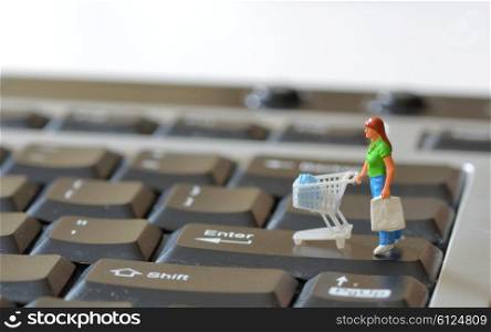 Miniature shopper with shopping cart on a computer keyboard