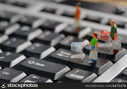 Miniature shoppers with shopping cart on a computer keyboard
