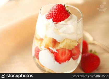 Miniature strawberry trifle in a drinking glass with whipped cream and pound cake cubes