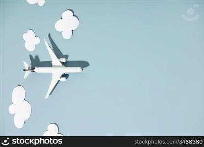 Miniature toy airplane and paper clouds on colorful background. Travel, vacations, tourism, airlines, low cost flights concept. Top view, flat lay.