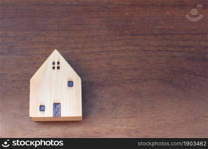Miniature wooden house on brown background with copy space