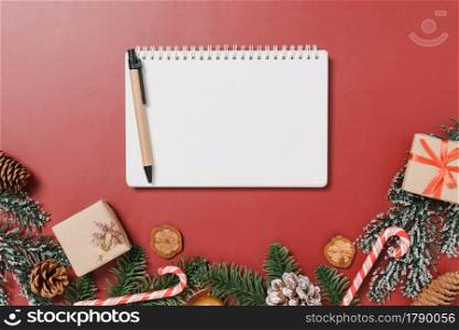 Minimal creative flat lay of winter christmas traditional composition and new year holiday season. Top view open mockup black notebook for text on red background. Mock up and copy space photography.
