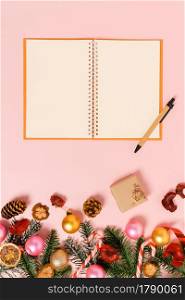 Minimal creative flat lay of winter christmas traditional composition and new year holiday season. Top view open mockup black notebook for text on pink background. Mock up and copy space photography.