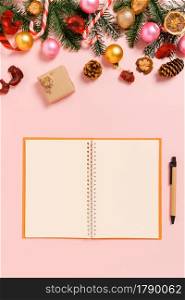Minimal creative flat lay of winter christmas traditional composition and new year holiday season. Top view open mockup black notebook for text on pink background. Mock up and copy space photography.