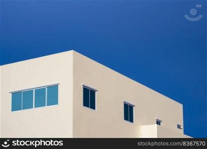 Minimal geometric architecture background of blue glass windows on pale yellow office building against blue clear sky in low angle and perspective side view