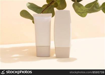 Minimal modern cosmetic product display with green leaves and tube on textured beige background with shadow overlay. Minimal product display