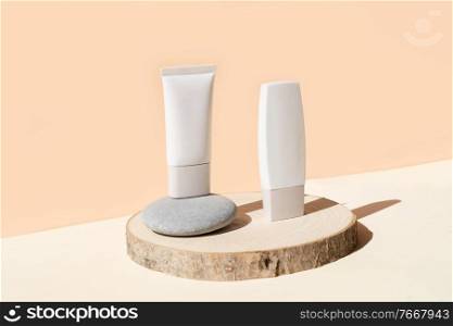 Minimal modern cosmetic products display with two tubes on neutral beige background with shadow overlay. Minimal product display